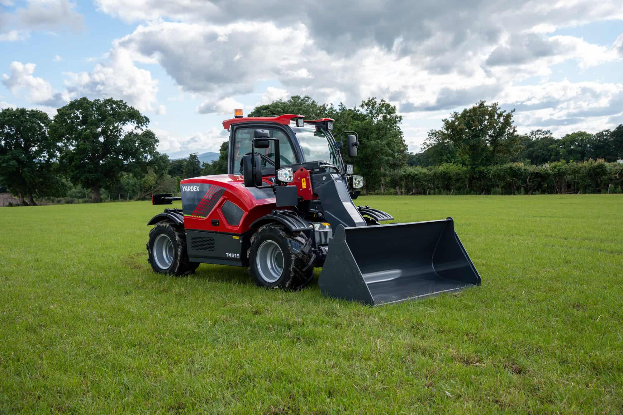 Yardex Group compact loader with bucket on green grass field.