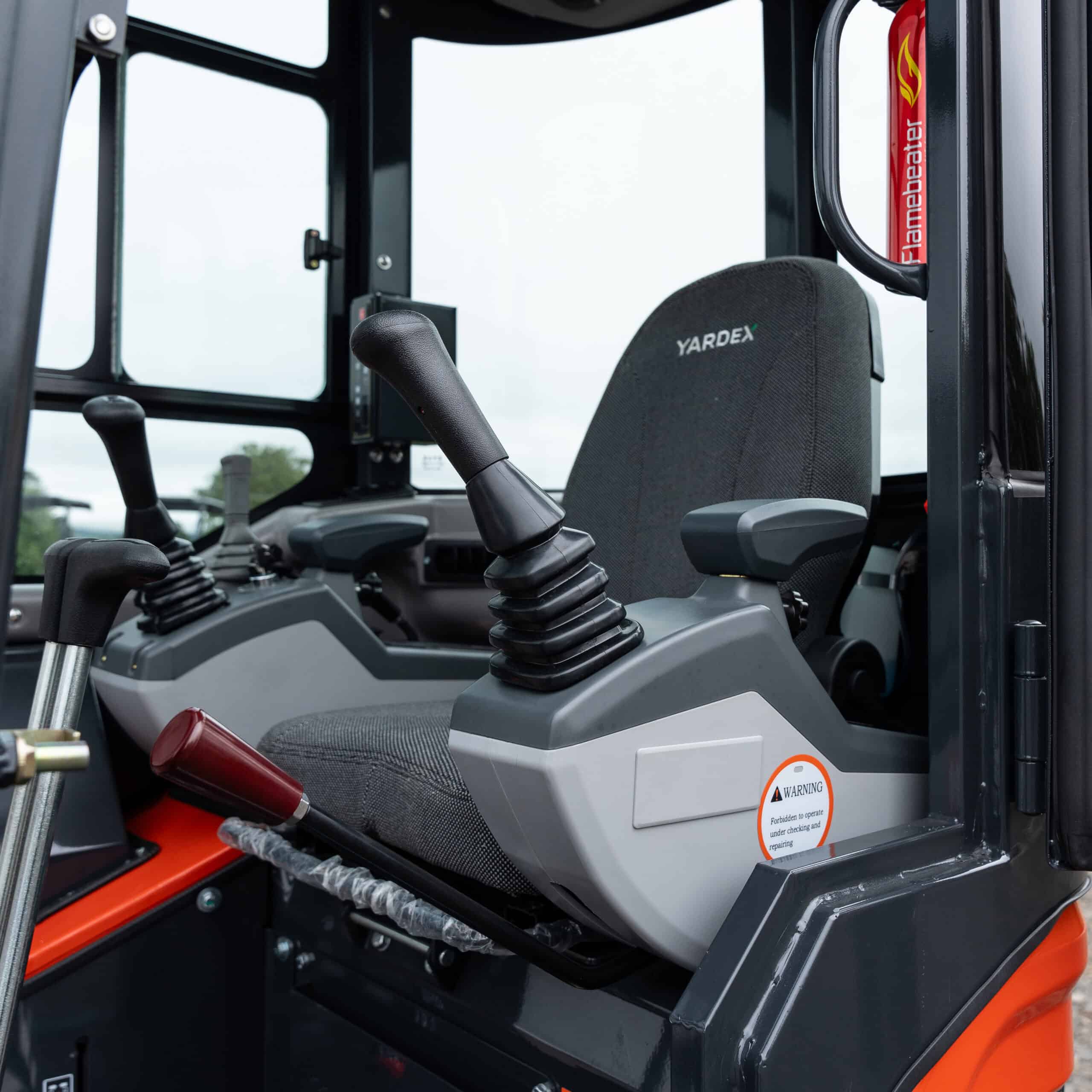 Close-up of Yardex Group construction machinery cabin with controls and seat.