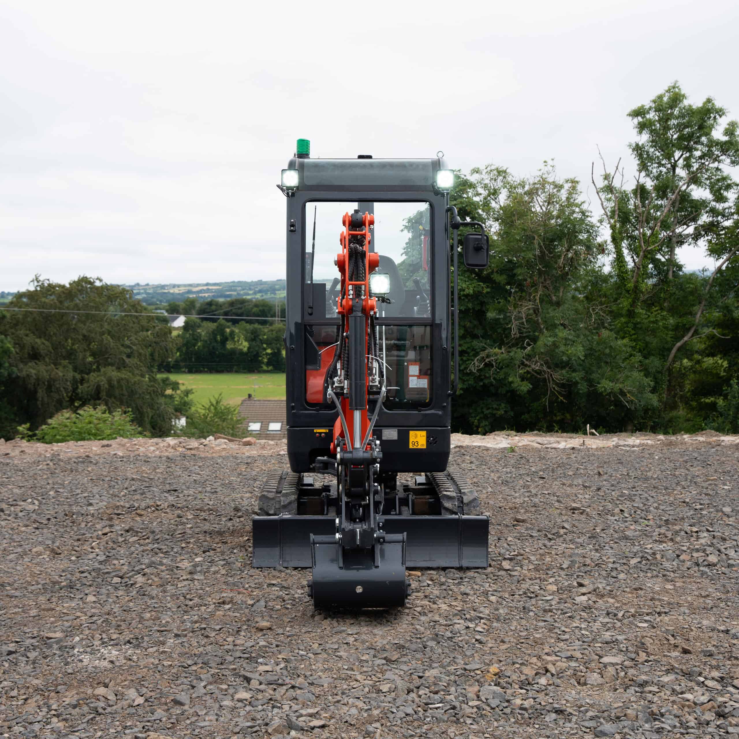 Compact excavator on construction site with scenic background.