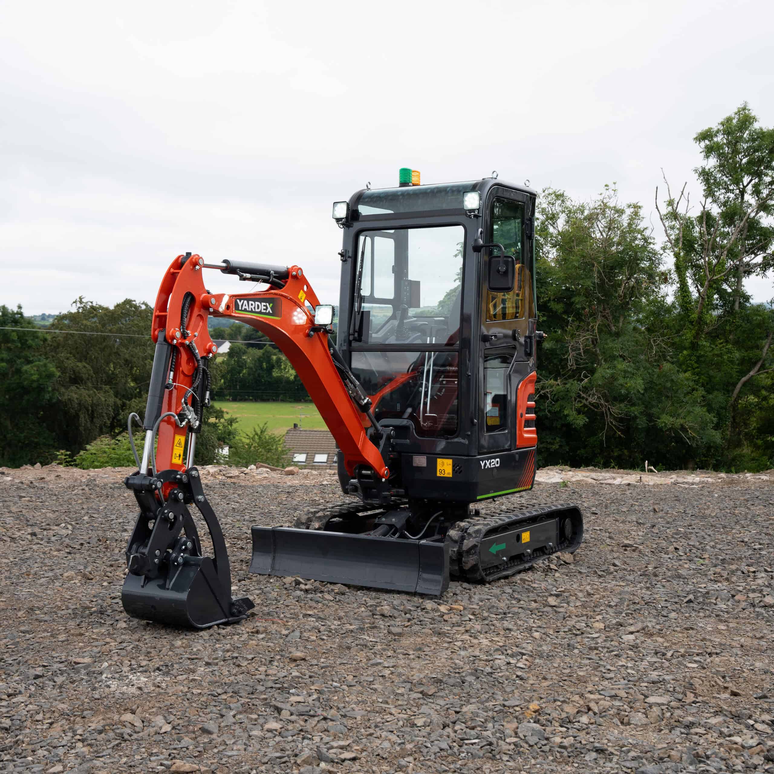 Yardex mini excavator on construction site with green background.