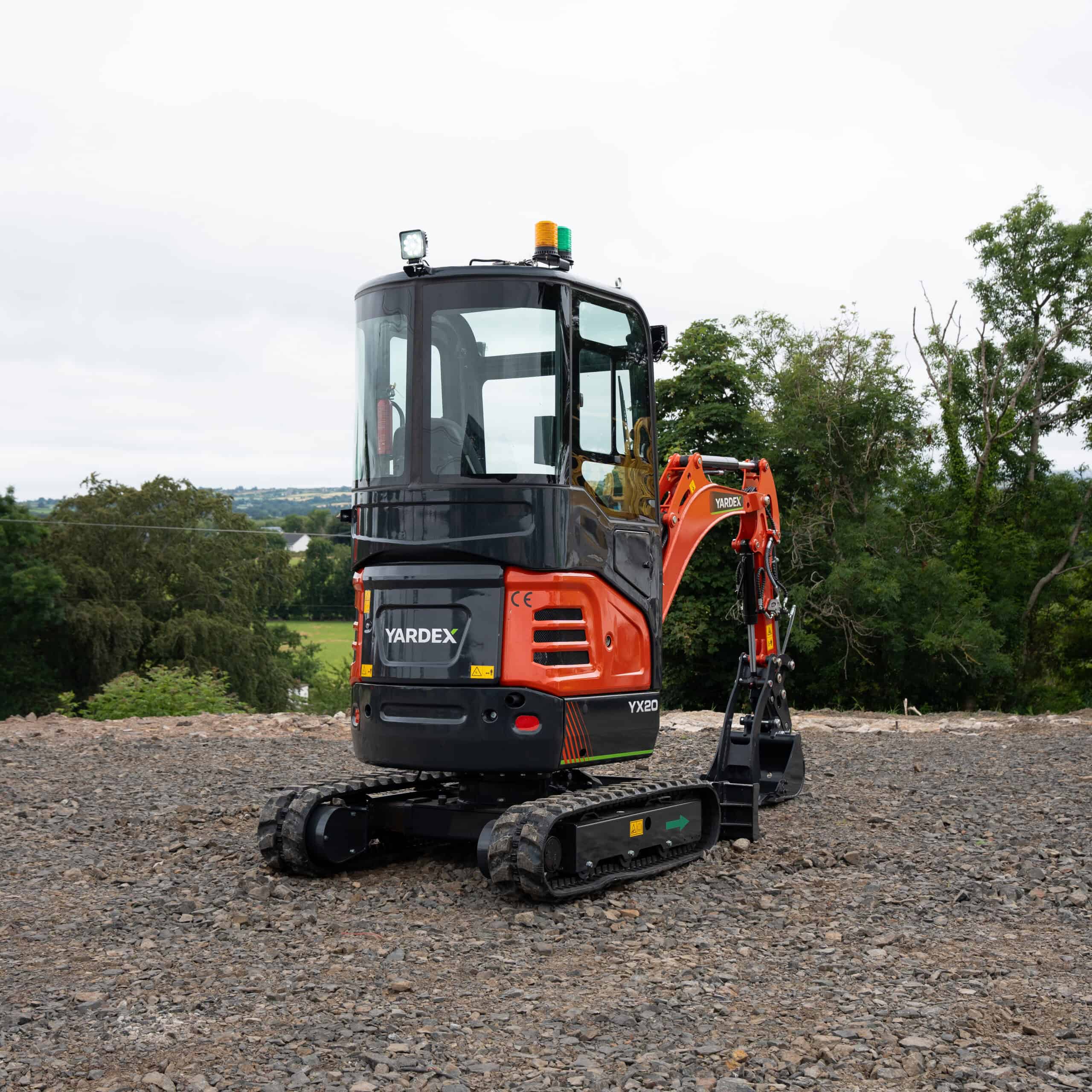 Compact Yardex mini excavator on construction site with trees in background.