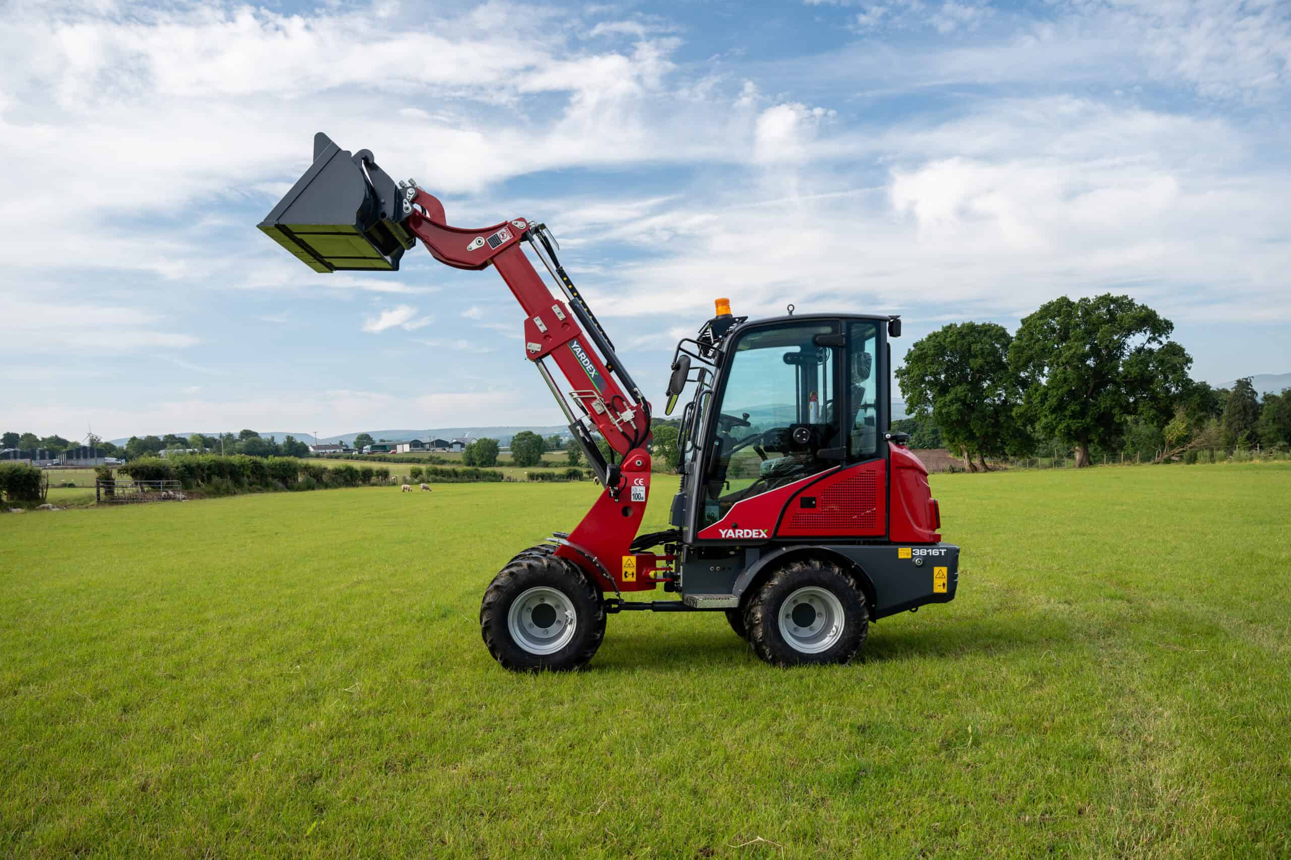 Yardex Group compact loader with front bucket on green field.