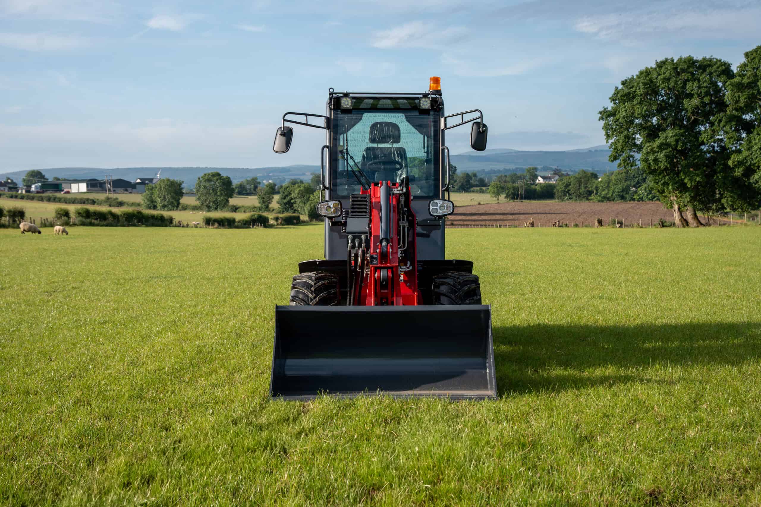 Yardex Group tractor with front loader on green field.