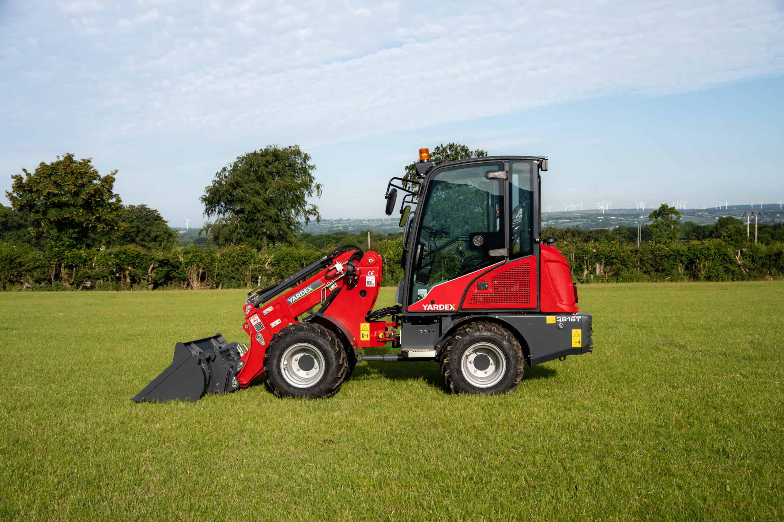 Yardex Group compact loader working on a grassy field.