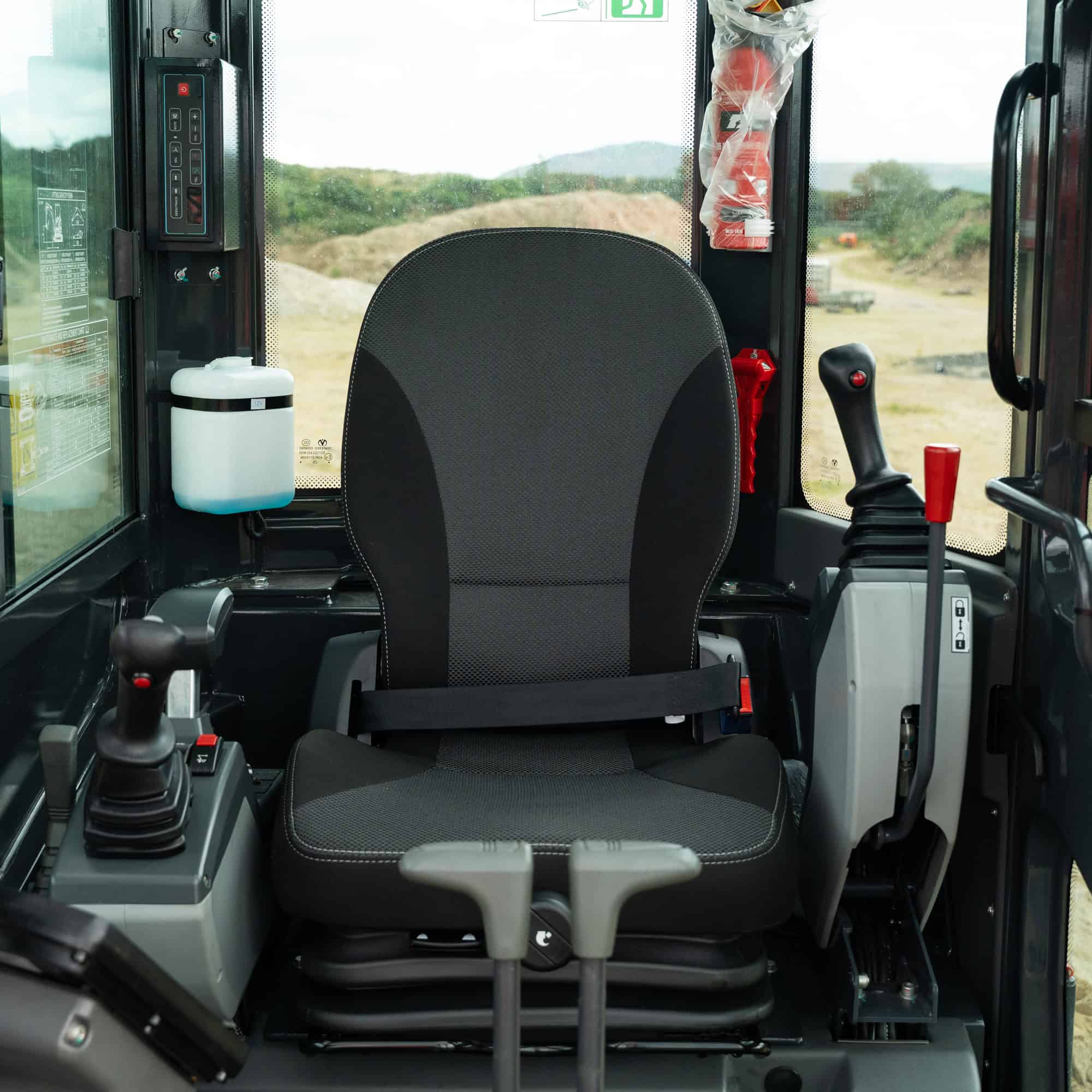 Construction vehicle cabin with controls and scenic background.
