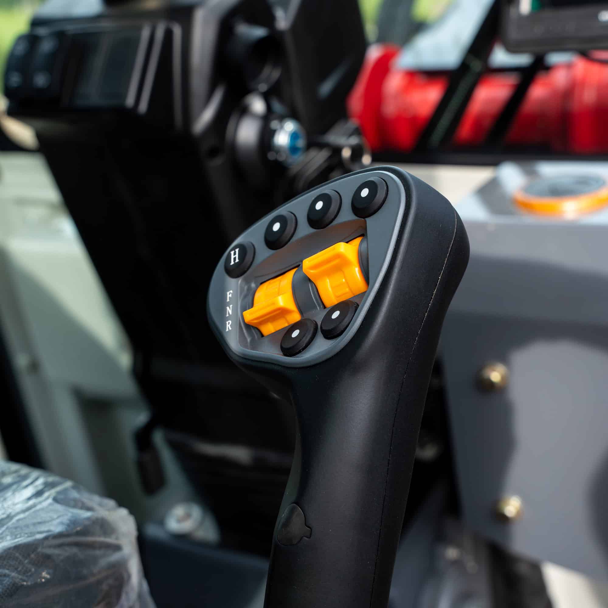 Construction machinery control lever with yellow switches and black handle.