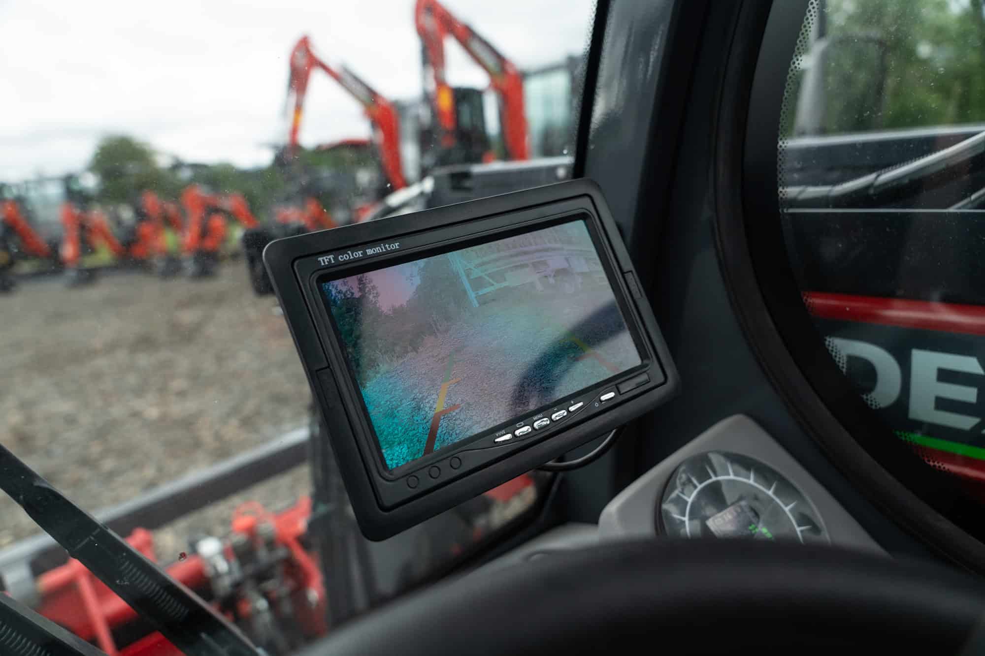 Construction machinery monitor inside a vehicle with excavators outside.