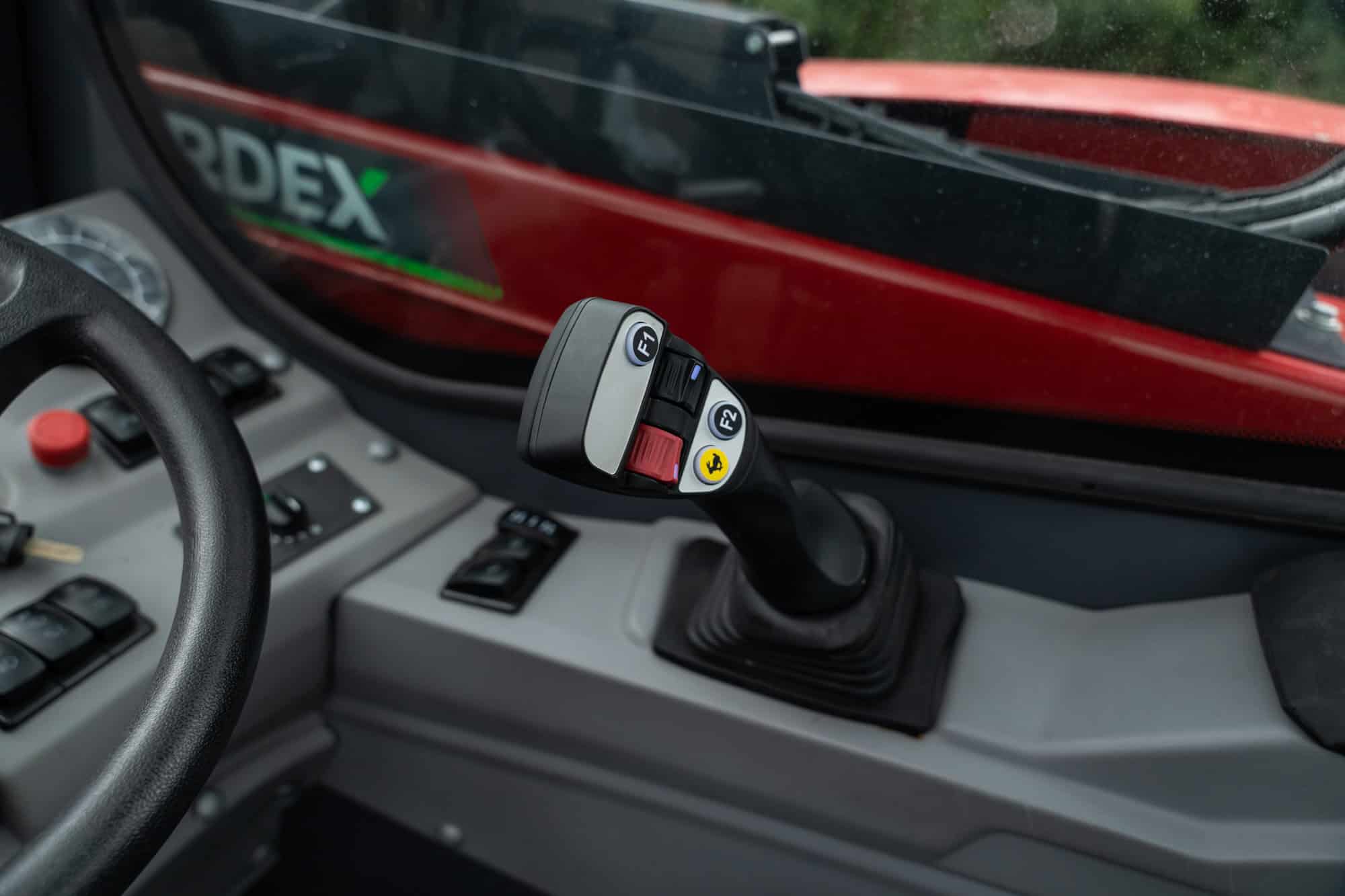 Close-up of Yardex Group machinery control joystick inside vehicle.